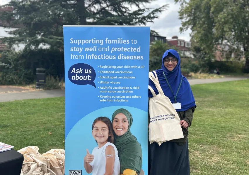Person infront of a banner displaying information about childhood vaccinations.