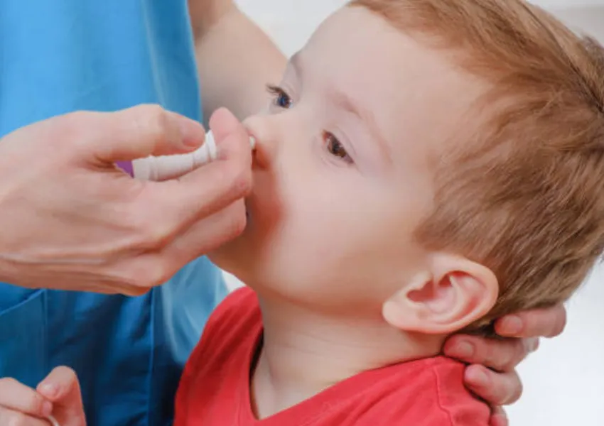 A toddle receiving a nasal spray