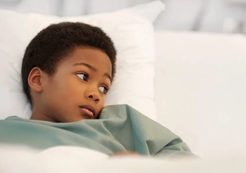 A young sick boy lying in bed