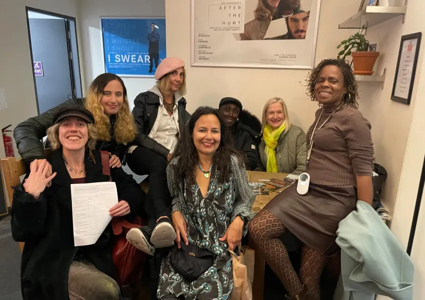 A group of people sitting and standing together smiling