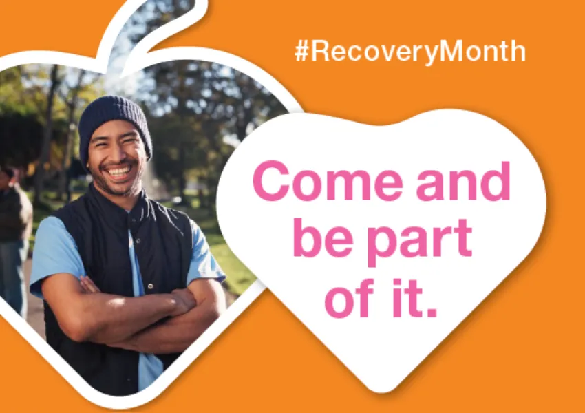 Smiling man in beanie, outside on sunny day. Orange background, pink writing in white heart 'come and be part of it'. #RecoveryMonth