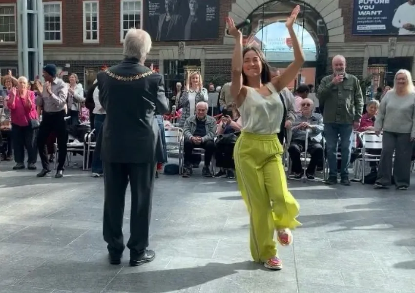 The mayor and a dancer in bright yellow trousers dancing in front of a crowd