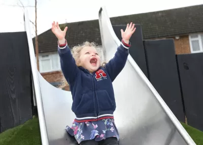 Child going down on slide arms in air
