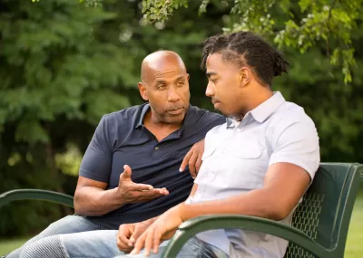 two men sat on a bench, having a conversation