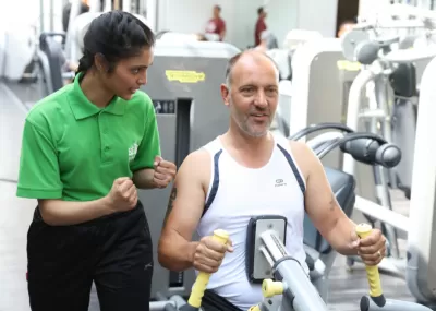 gym staff member encouraging a man on an exercise machine