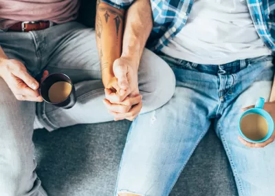 two people on a sofa holding hands, no faces visible in shot