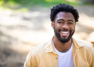 smiling black man wearing a yellow shirt