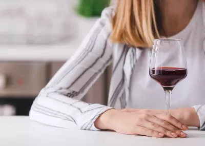 Woman holding glass of red wine, face not visible