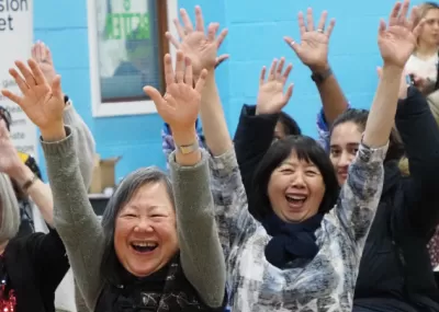 Women doing chair exercises, smiling, with hands in air