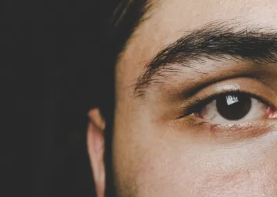 Close up image of a man's face, zooming in on his right eye which is looking directly into the camera.