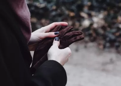 Person holding brown gloves outside in the cold.