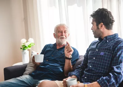 Older man with mug speaking to younger man