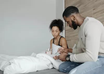 Woman feeling unwell with a glass of water,. Man giving her medication