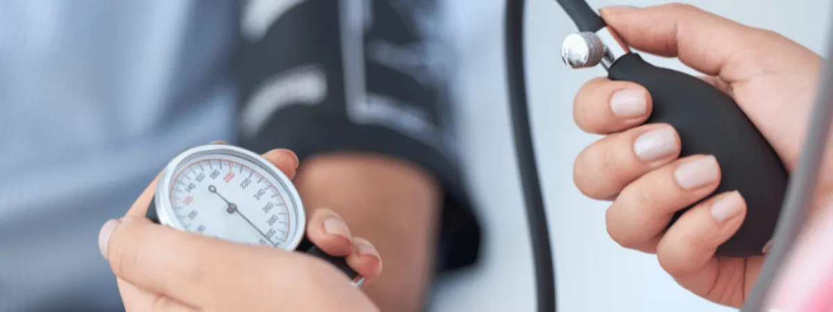 An arm with a blood pressure monitor attached, and two hands performing the blood pressure check.