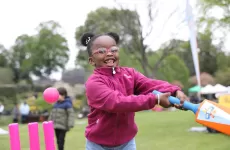 Smiling young girl swinging cricket bat