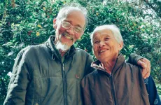 older couple smiling in front of flowering plant