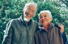 older couple smiling in front of flowering plant